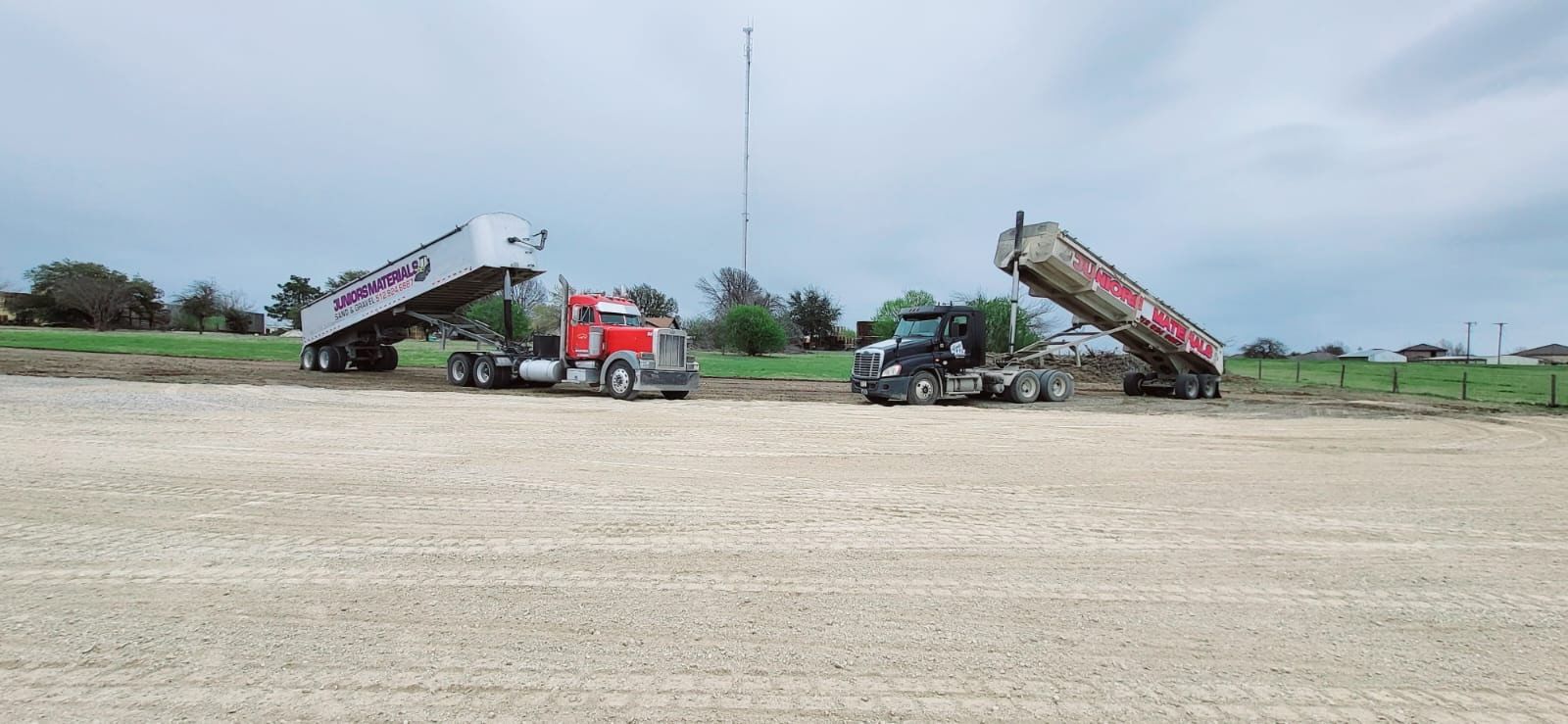 Two Juniors Materials dump trucks dropping road base on a large pad.